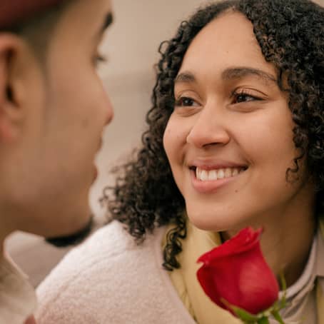 mujer feliz porque pareja le ha regalado una rosa roja